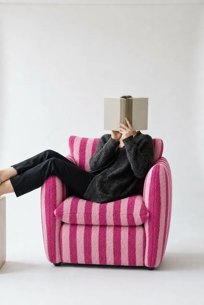 A pink striped armchair with a seated figure reading