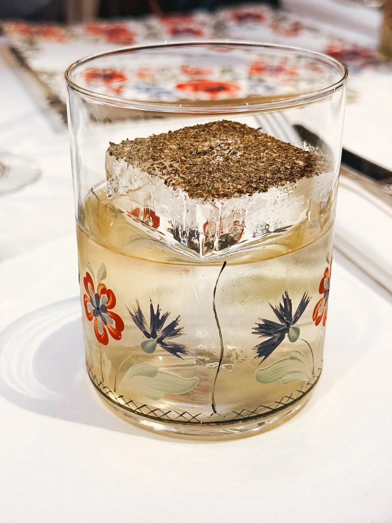 A cocktail in a folk-patterned glass