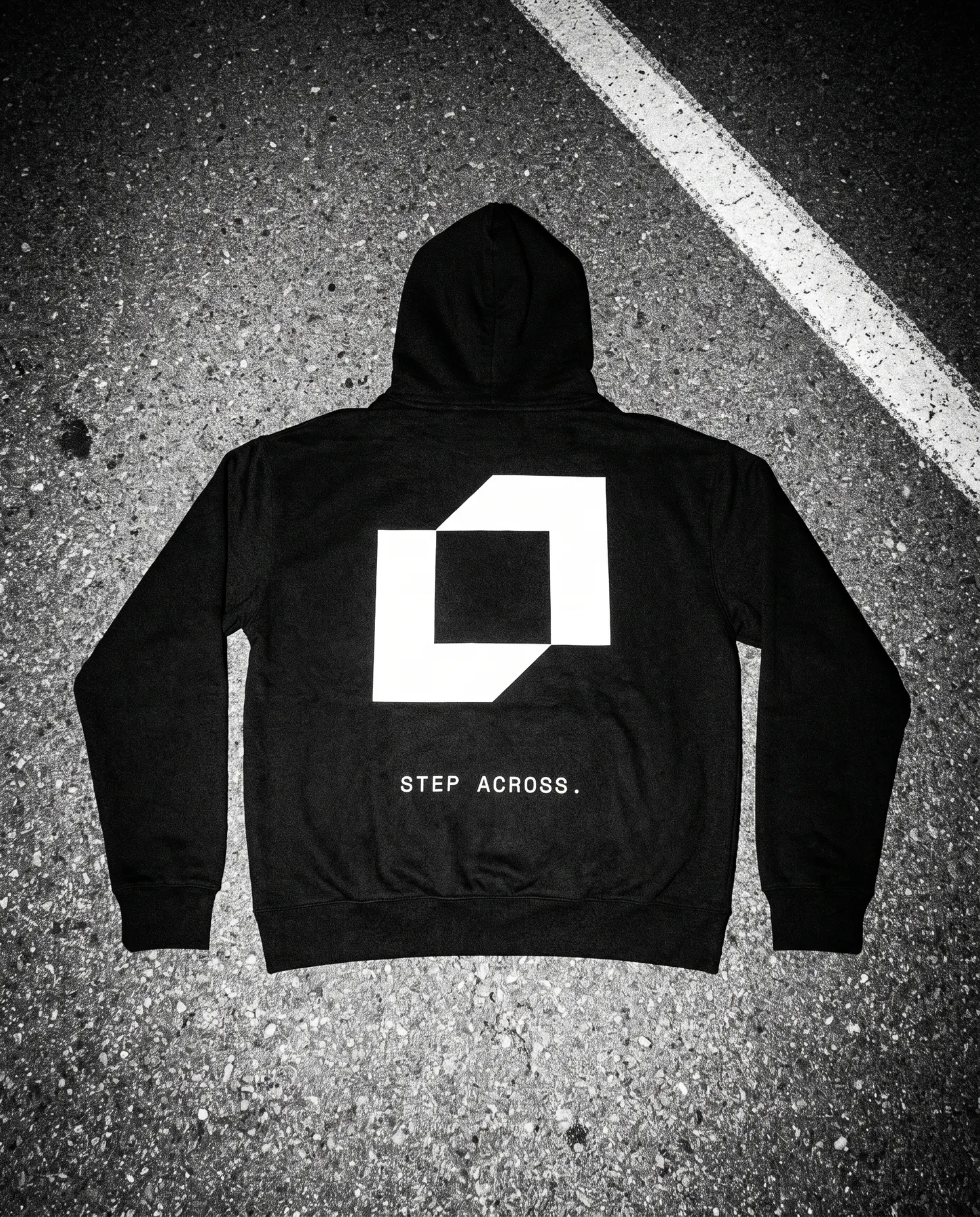 Black hoodie laid on asphalt, the symbol and Step across. on the back