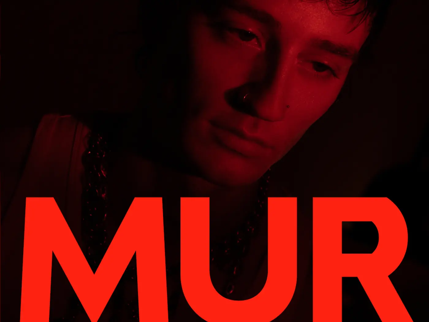 A face turned to camera in near darkness with MUR set large in red across the lower half of the frame