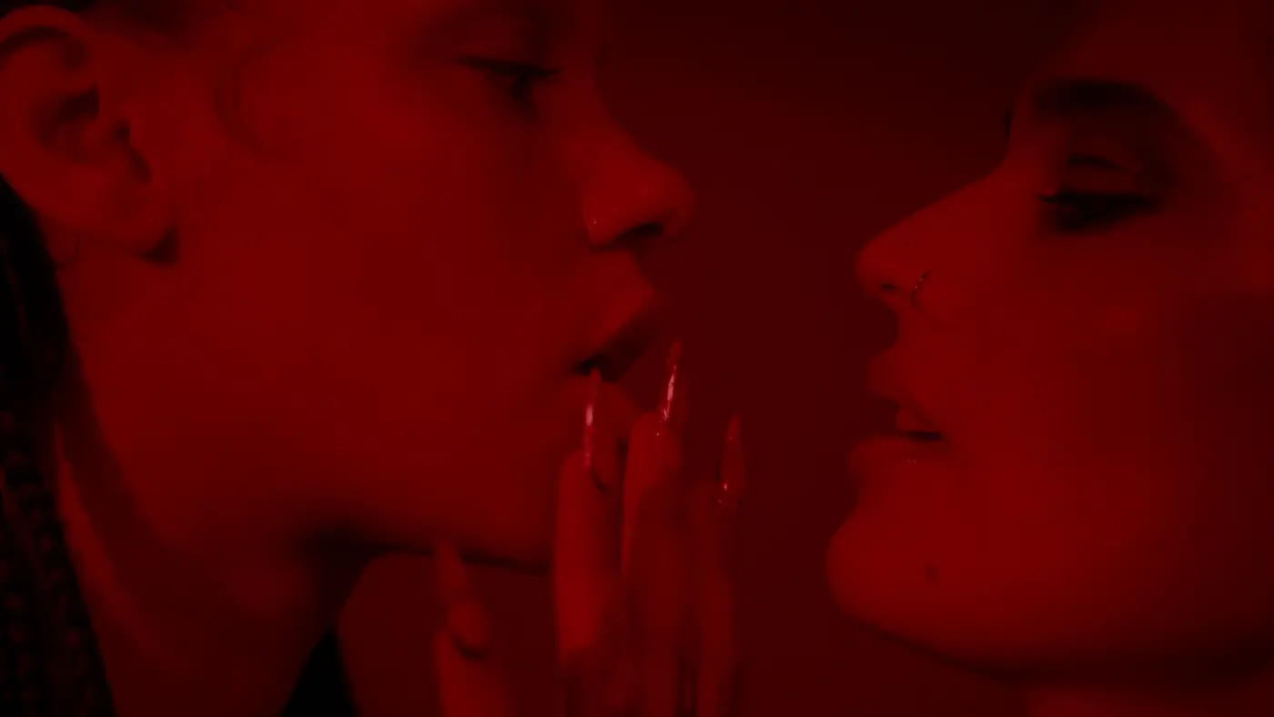 A raised hand between two faces turned towards one another
