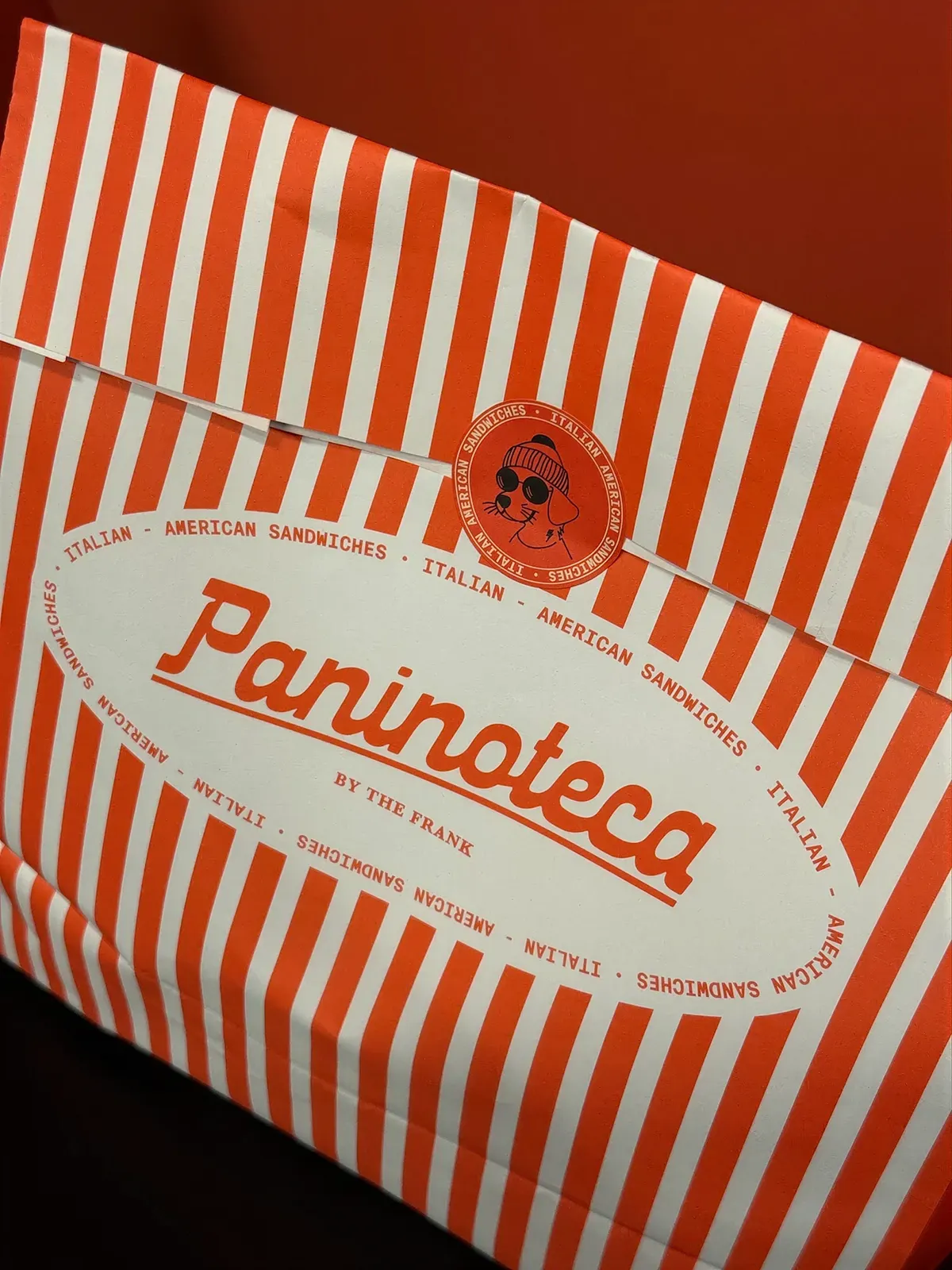 Striped takeaway bag with the oval badge.