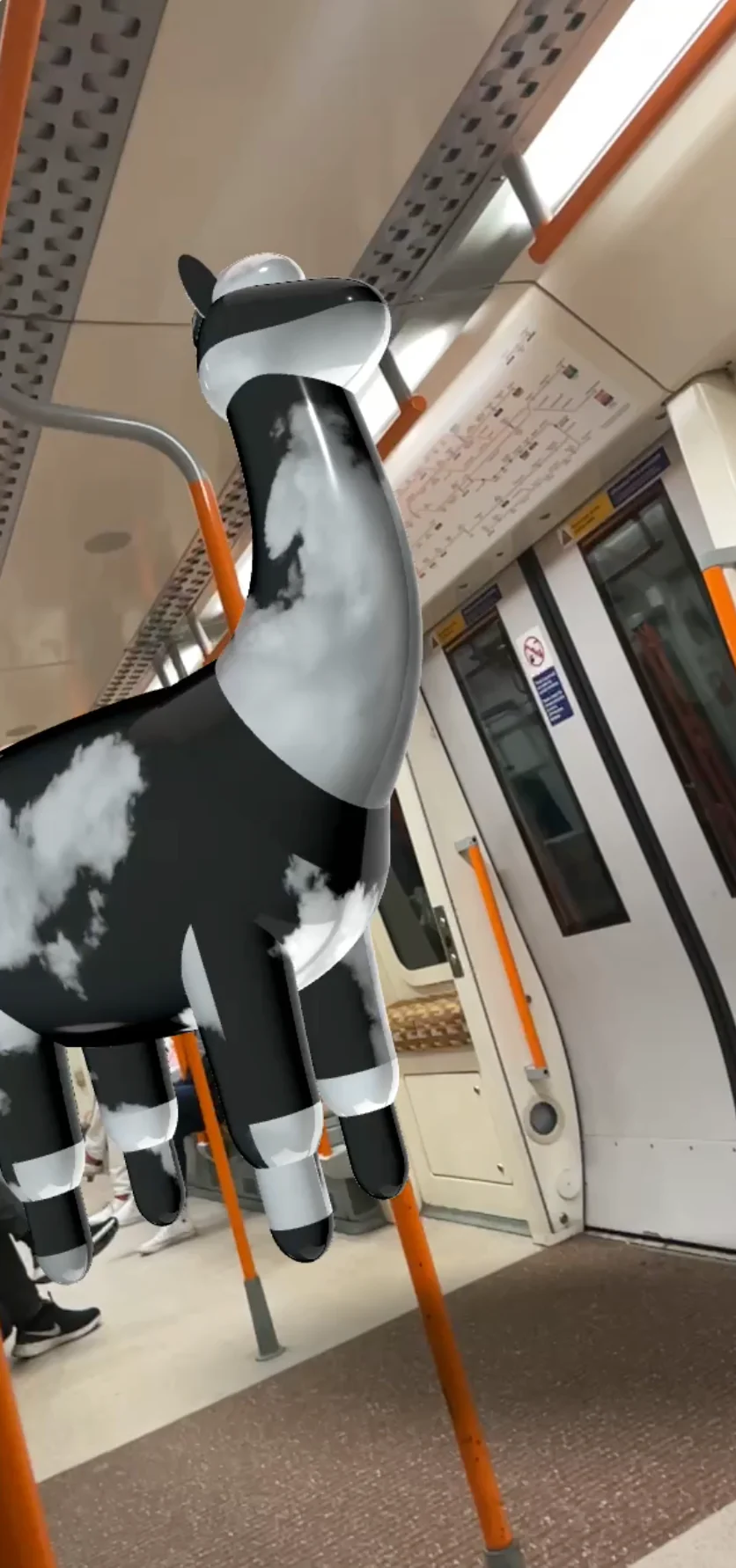 Augmented reality: a black and white alpaca standing in a London Overground carriage