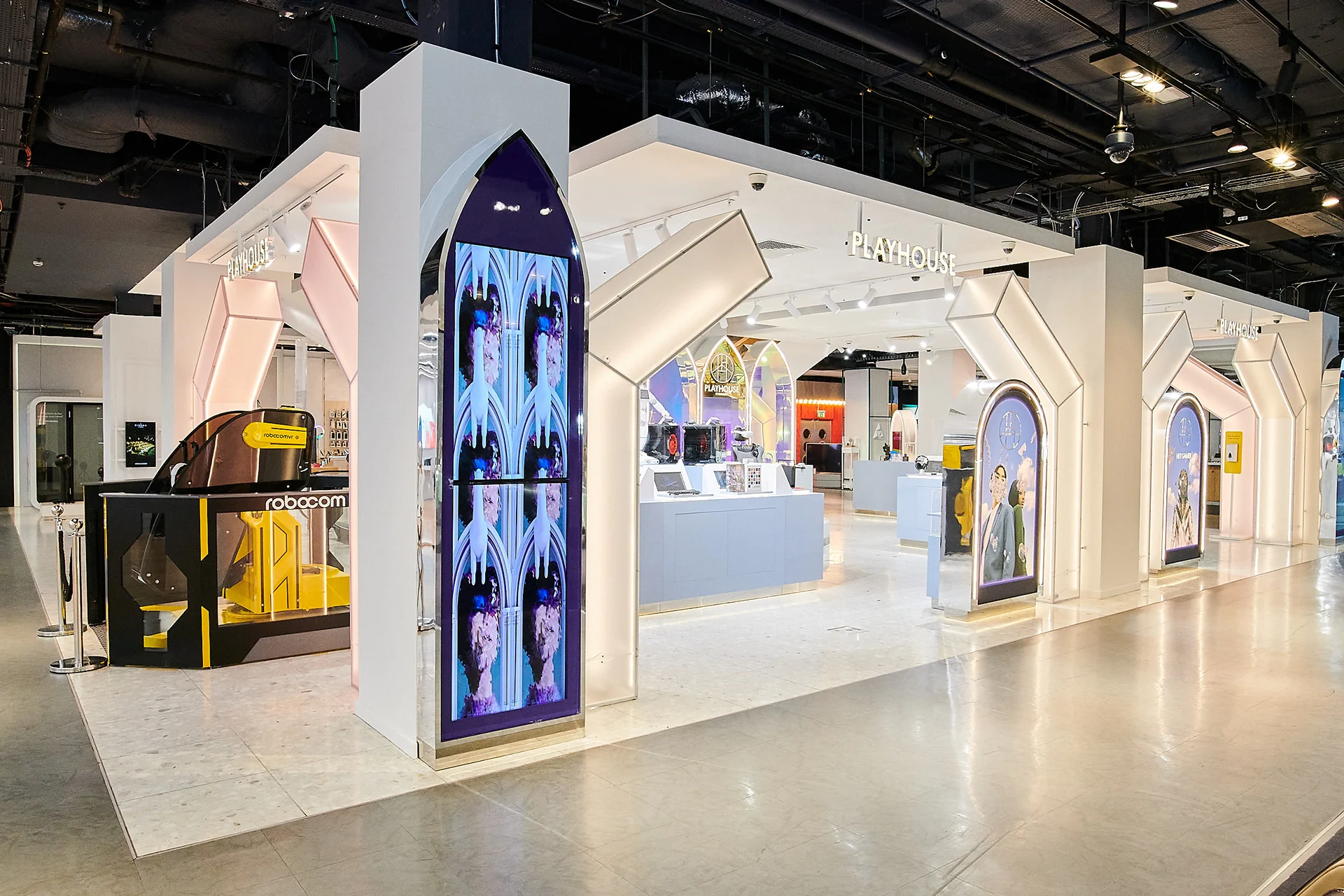 The Playhouse store seen from the side: an arch-shaped screen with campaign portraits at the corner of the space